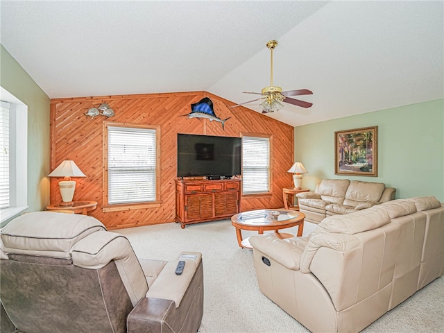 carpeted living room featuring ceiling fan, wooden walls, and vaulted ceiling