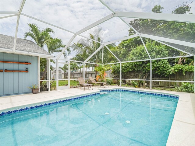 view of pool with glass enclosure, a patio area, and a storage unit