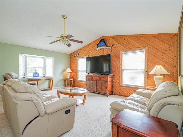 living room with wood walls, lofted ceiling, light carpet, and ceiling fan