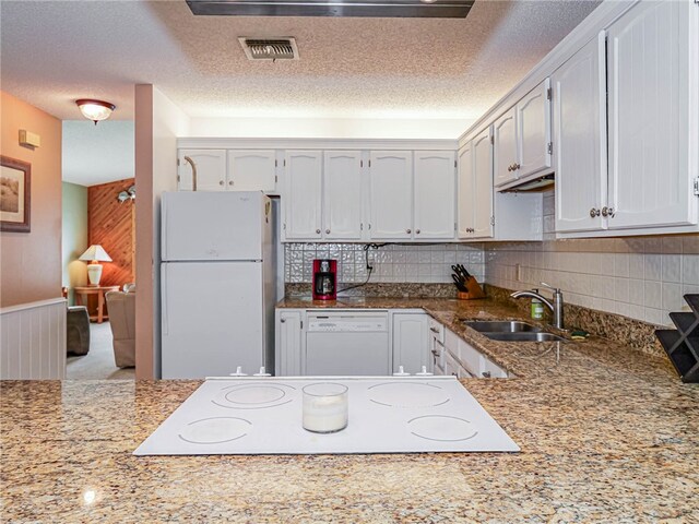 kitchen with wood walls, white cabinetry, white appliances, and sink