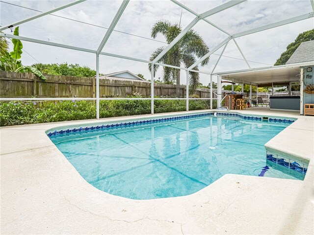 view of swimming pool featuring glass enclosure and a patio area