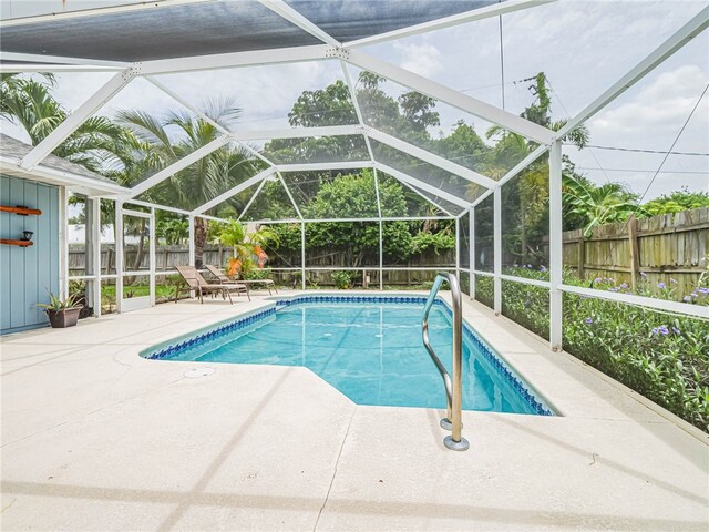 view of pool featuring glass enclosure and a patio