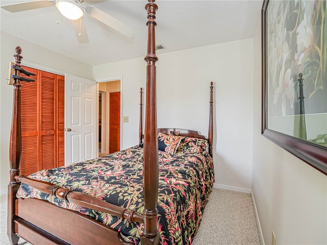 carpeted bedroom with a textured ceiling, ceiling fan, and a closet