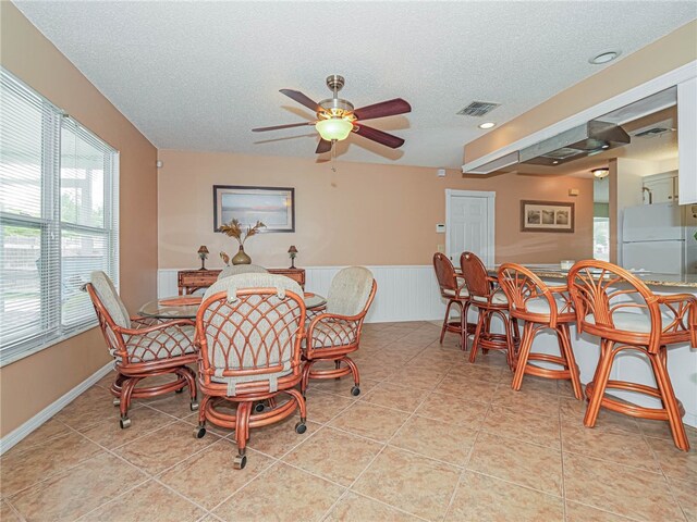 dining space featuring a textured ceiling, ceiling fan, and light tile patterned flooring