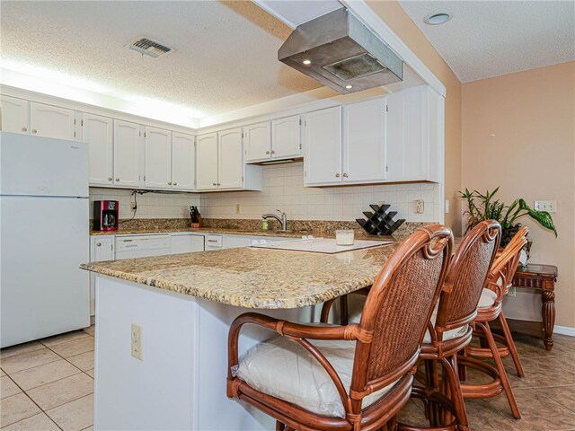 kitchen with backsplash, a textured ceiling, white fridge, and range hood