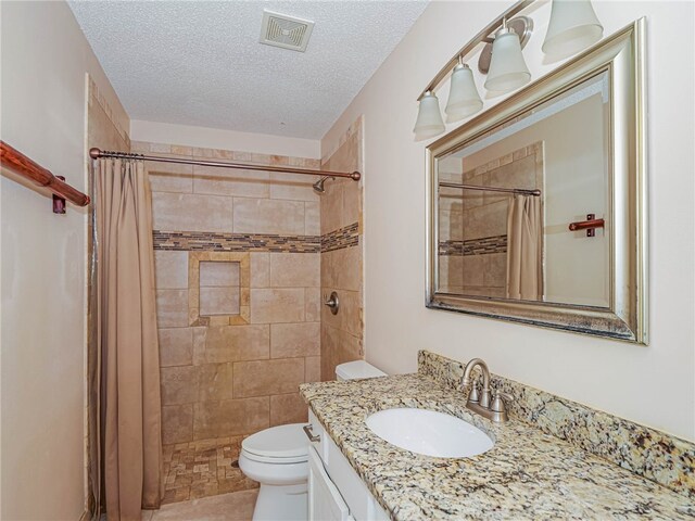 bathroom featuring vanity, curtained shower, a textured ceiling, and toilet