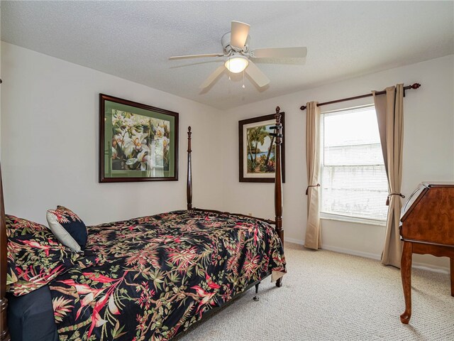 carpeted bedroom featuring ceiling fan and a textured ceiling