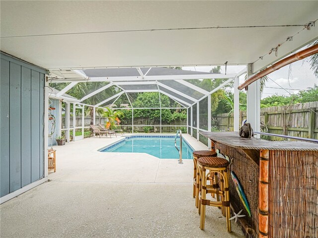 view of swimming pool featuring a bar, glass enclosure, and a patio area