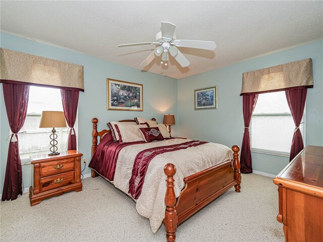 carpeted bedroom featuring ceiling fan, multiple windows, and a textured ceiling