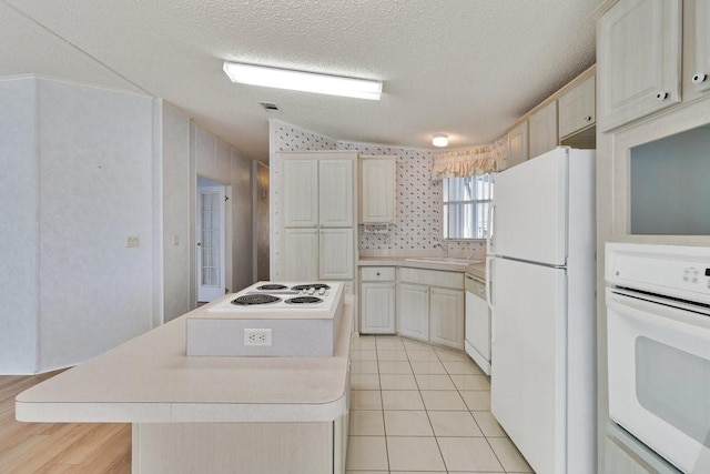 kitchen with sink, white appliances, a center island, and a textured ceiling