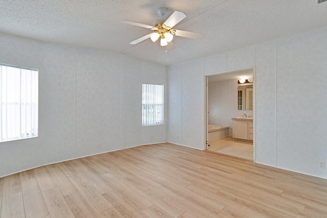 spare room featuring light wood-type flooring, ceiling fan, and a textured ceiling