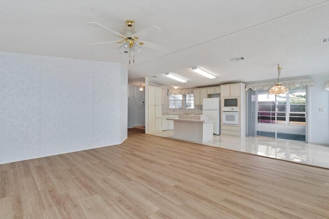 unfurnished living room featuring a textured ceiling, ceiling fan, and light hardwood / wood-style flooring