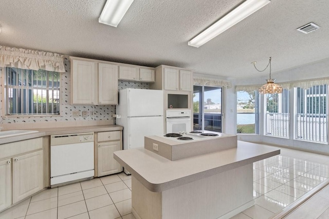 kitchen with white appliances, a textured ceiling, a center island, hanging light fixtures, and light tile patterned flooring