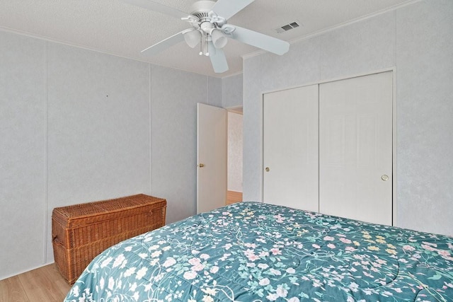 bedroom with a closet, ceiling fan, crown molding, and wood-type flooring