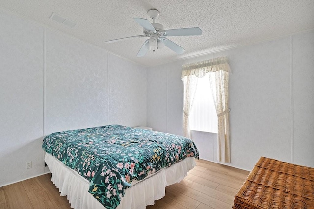 bedroom featuring ceiling fan, hardwood / wood-style floors, and a textured ceiling