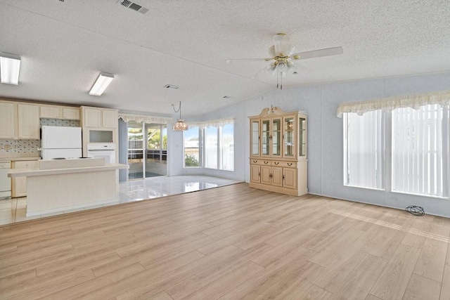 unfurnished living room with a textured ceiling, light hardwood / wood-style flooring, lofted ceiling, and ceiling fan with notable chandelier