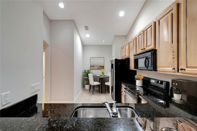 kitchen featuring tile patterned flooring, black appliances, sink, light brown cabinets, and dark stone countertops