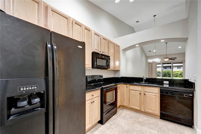 kitchen with sink, black appliances, dark stone counters, light brown cabinetry, and hanging light fixtures