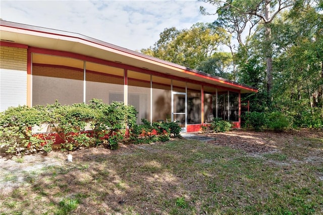 rear view of house with a yard and a sunroom