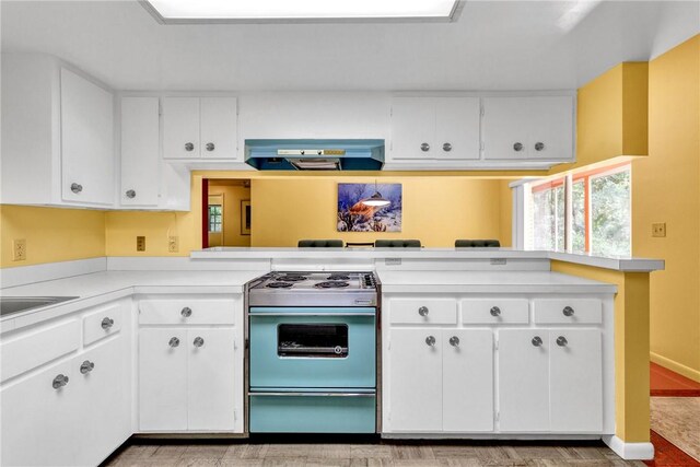 kitchen with white cabinetry, range, kitchen peninsula, and range hood