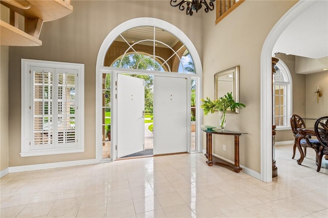 foyer featuring a chandelier, light tile patterned floors, and a towering ceiling