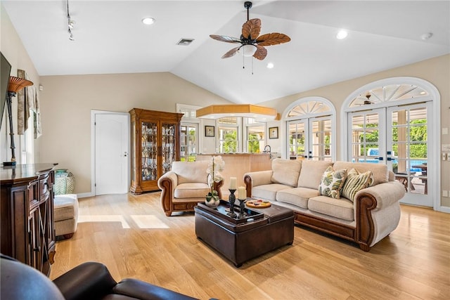 living room featuring ceiling fan, french doors, vaulted ceiling, and light wood-type flooring