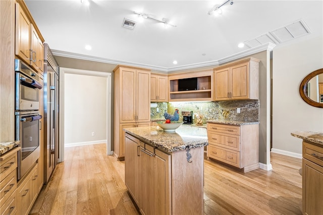 kitchen with a center island, light stone countertops, crown molding, and double oven