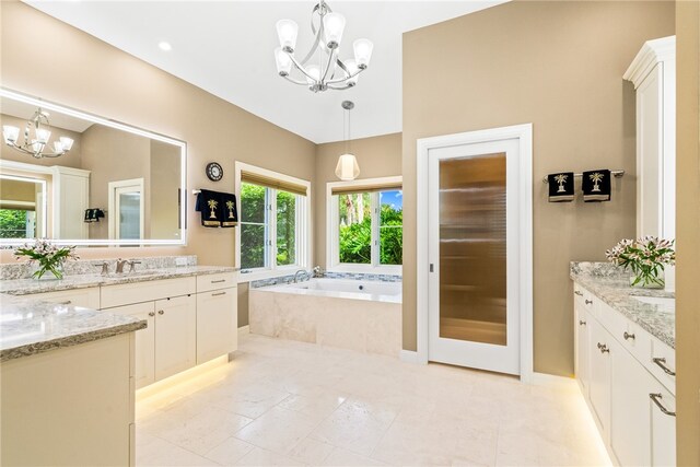 bathroom with a notable chandelier, vanity, and tiled bath