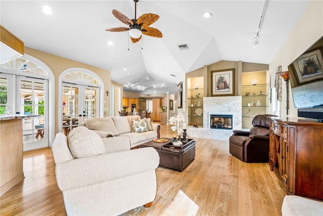 living room with french doors, track lighting, vaulted ceiling, ceiling fan, and light hardwood / wood-style floors