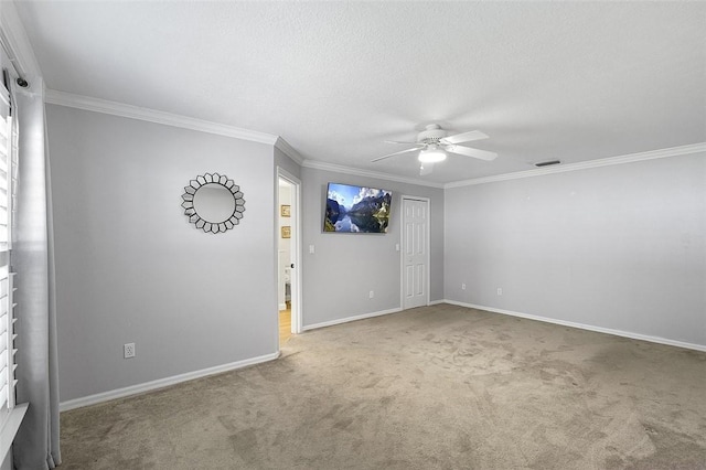 empty room featuring baseboards, visible vents, carpet, ceiling fan, and crown molding