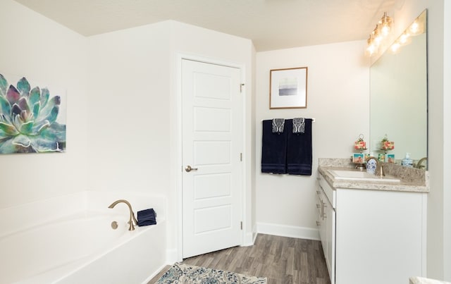 bathroom with hardwood / wood-style floors, vanity, and a tub