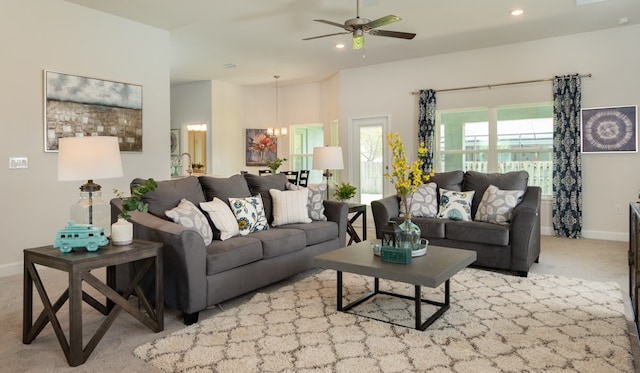 living room featuring light carpet and ceiling fan with notable chandelier