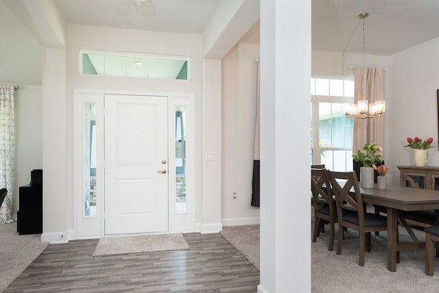 entryway featuring dark colored carpet, plenty of natural light, and a notable chandelier