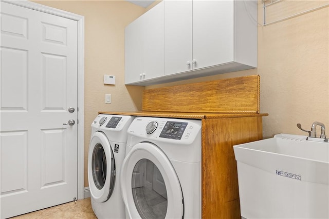 laundry room featuring cabinet space, washing machine and dryer, a sink, and a textured wall