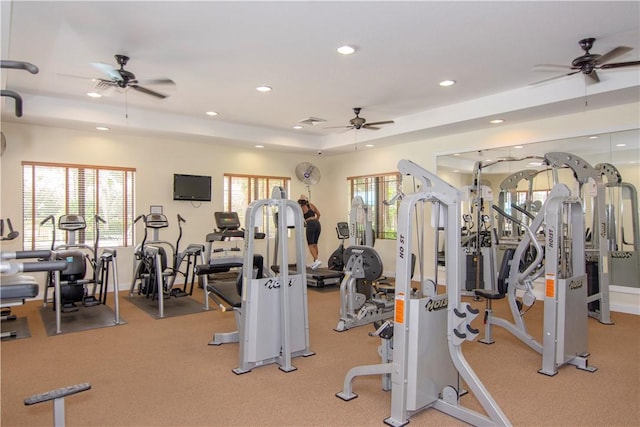 exercise room with a tray ceiling, recessed lighting, visible vents, ceiling fan, and baseboards