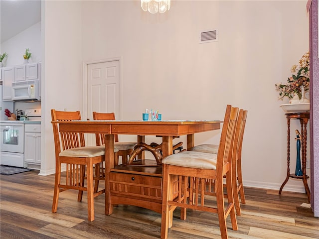 dining room featuring high vaulted ceiling, an inviting chandelier, and light hardwood / wood-style flooring