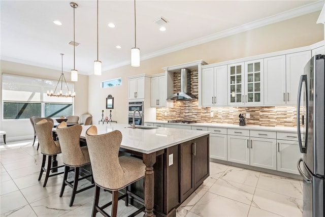 kitchen with a center island with sink, white cabinetry, wall chimney range hood, and stainless steel appliances