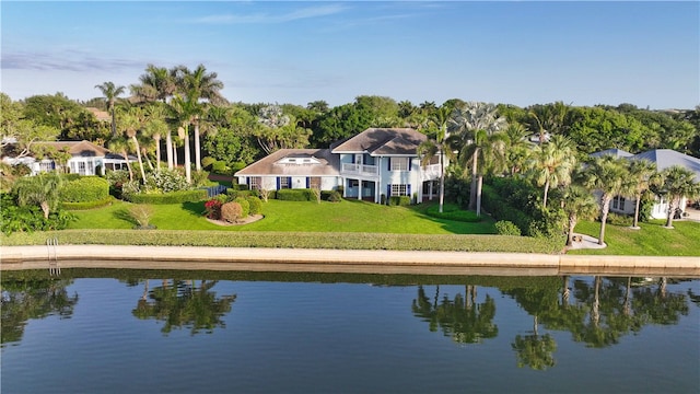 rear view of house featuring a water view and a lawn