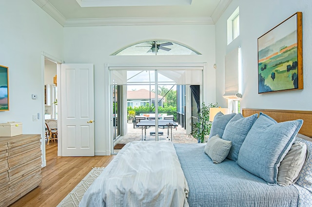 bedroom featuring access to outside, light hardwood / wood-style floors, a high ceiling, and crown molding