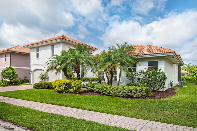 mediterranean / spanish house featuring a front yard, central AC, and a garage