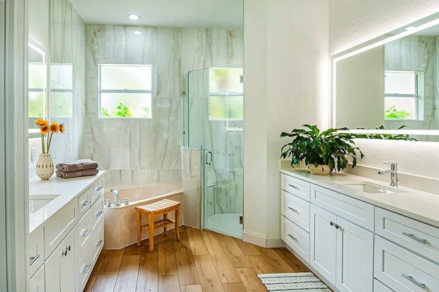 bathroom with wood-type flooring, vanity, and shower with separate bathtub