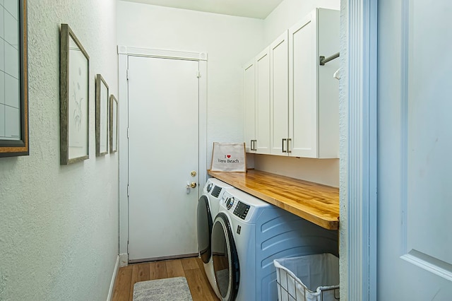 clothes washing area with cabinets, separate washer and dryer, and light hardwood / wood-style flooring