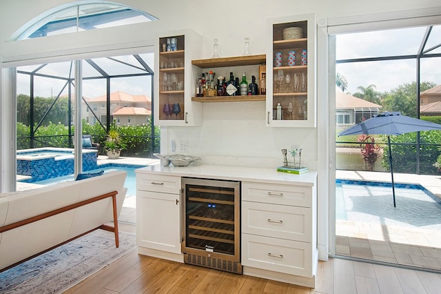 bar with white cabinetry, light wood-type flooring, and wine cooler