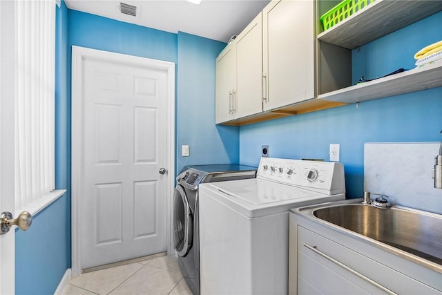 919 Island Club Sq, Vero Beach, FL 32963 - laundry area with visible vents, cabinet space, a sink, light tile patterned flooring, and washer and clothes dryer