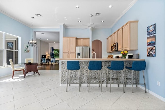919 Island Club Sq, Vero Beach, FL 32963 - kitchen featuring light brown cabinetry, crown molding, a breakfast bar area, stainless steel appliances, and visible vents
