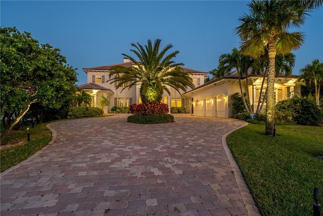 mediterranean / spanish-style home with a garage and a lawn