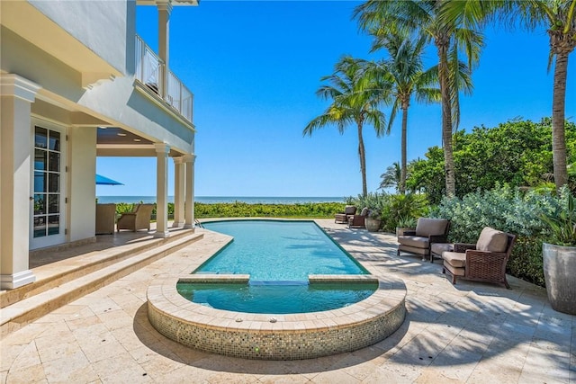 view of pool with a patio, a water view, and an in ground hot tub