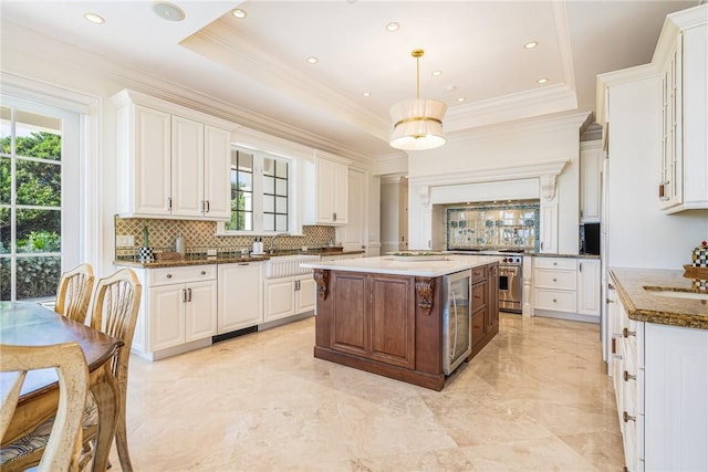 kitchen featuring white cabinetry, tasteful backsplash, a center island, a raised ceiling, and pendant lighting