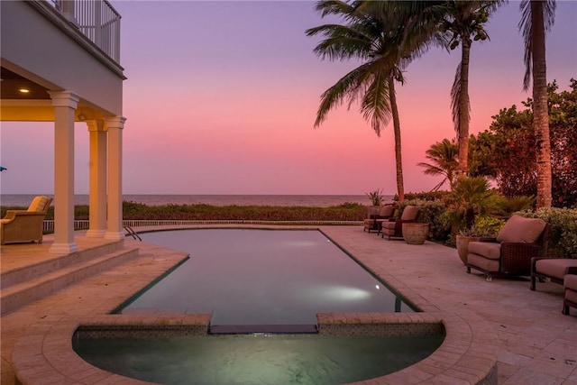 pool at dusk featuring a water view, outdoor lounge area, and a patio area