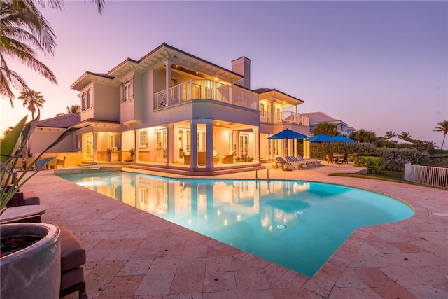 pool at dusk with a patio area